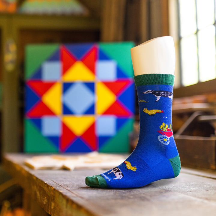 Side shot of the unisex barnyard VT Foodbank crew lifestock sock on a mannequin foot on a wood table