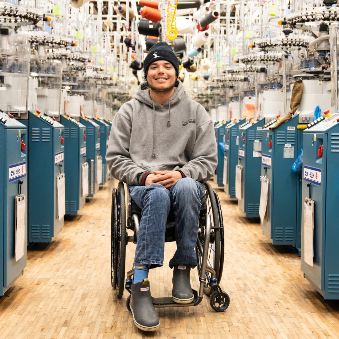 Trevor Kennison seated in his wheelchair in the Darn Tough mill, smiling away