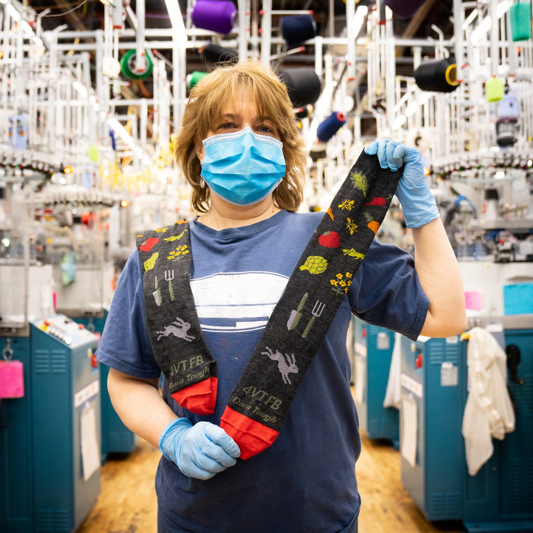 A Darn Tough employee in the mill holding the Vermont foodbank sock