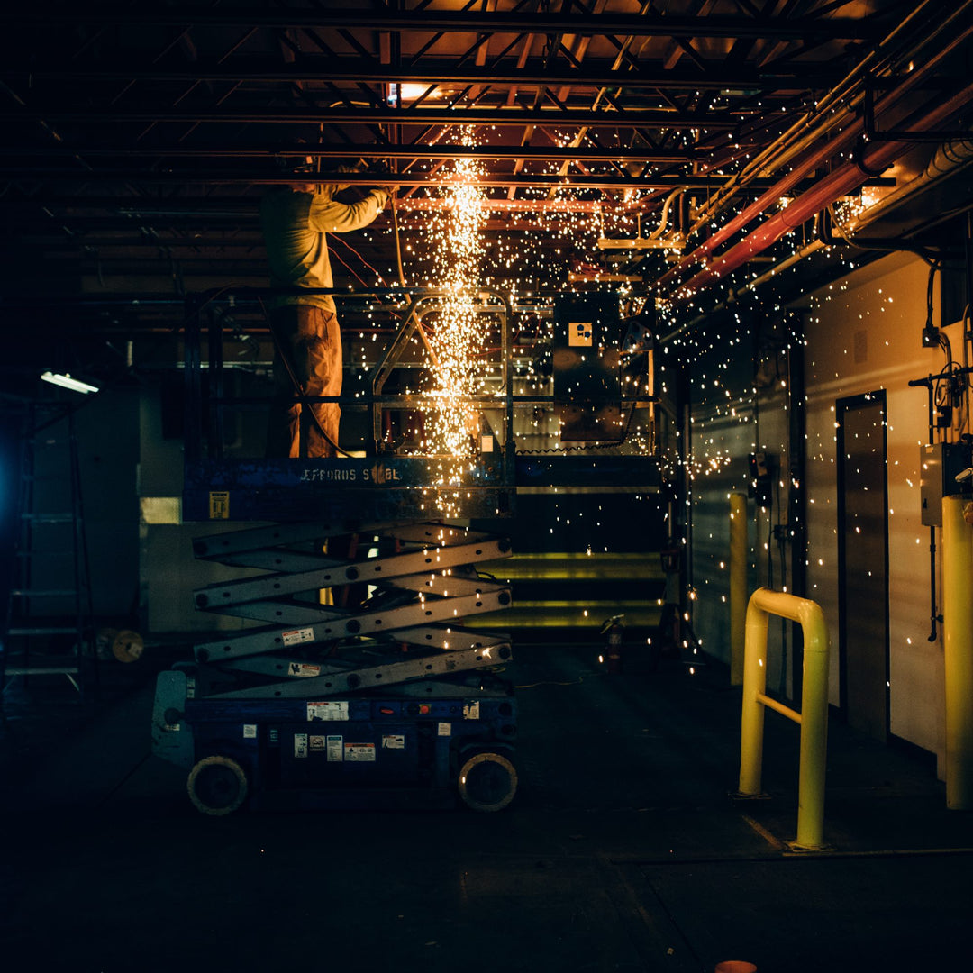 Worker in factory doing some welding and sending sparks flying