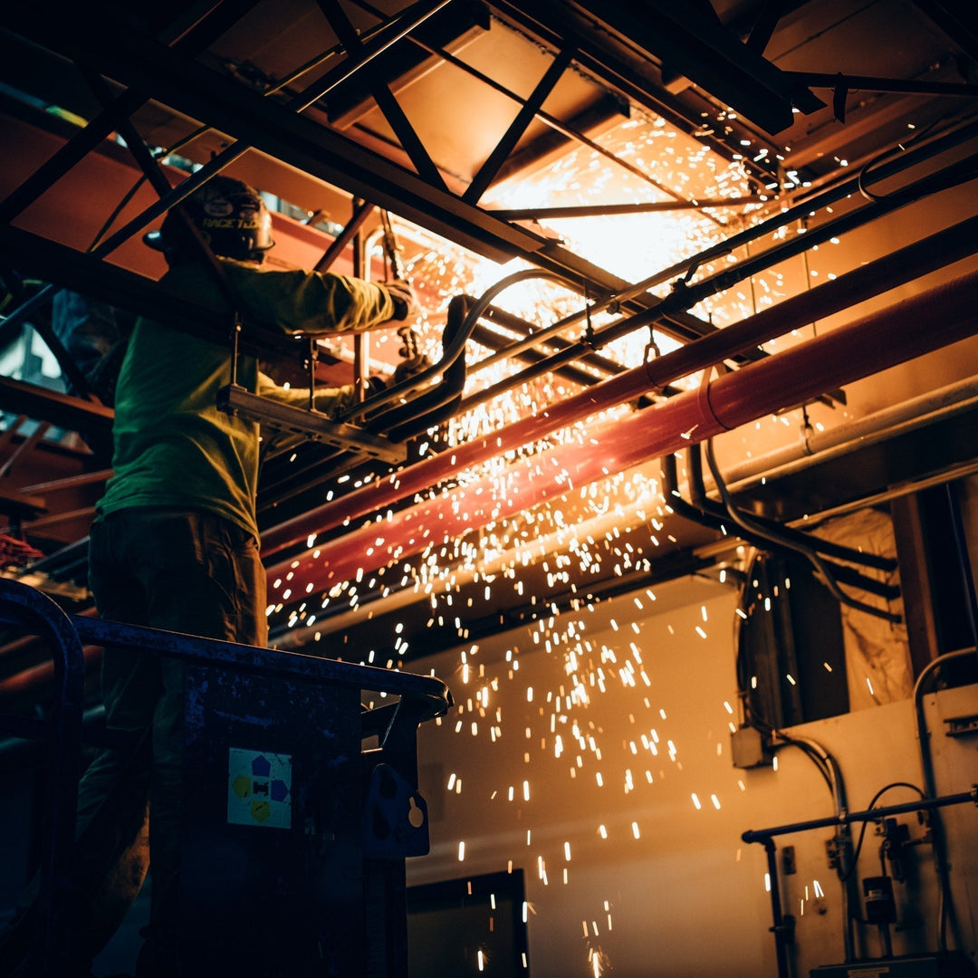 Welder working on pipe, sparks flying, good thing he's wearing fire resistant socks from darn tough