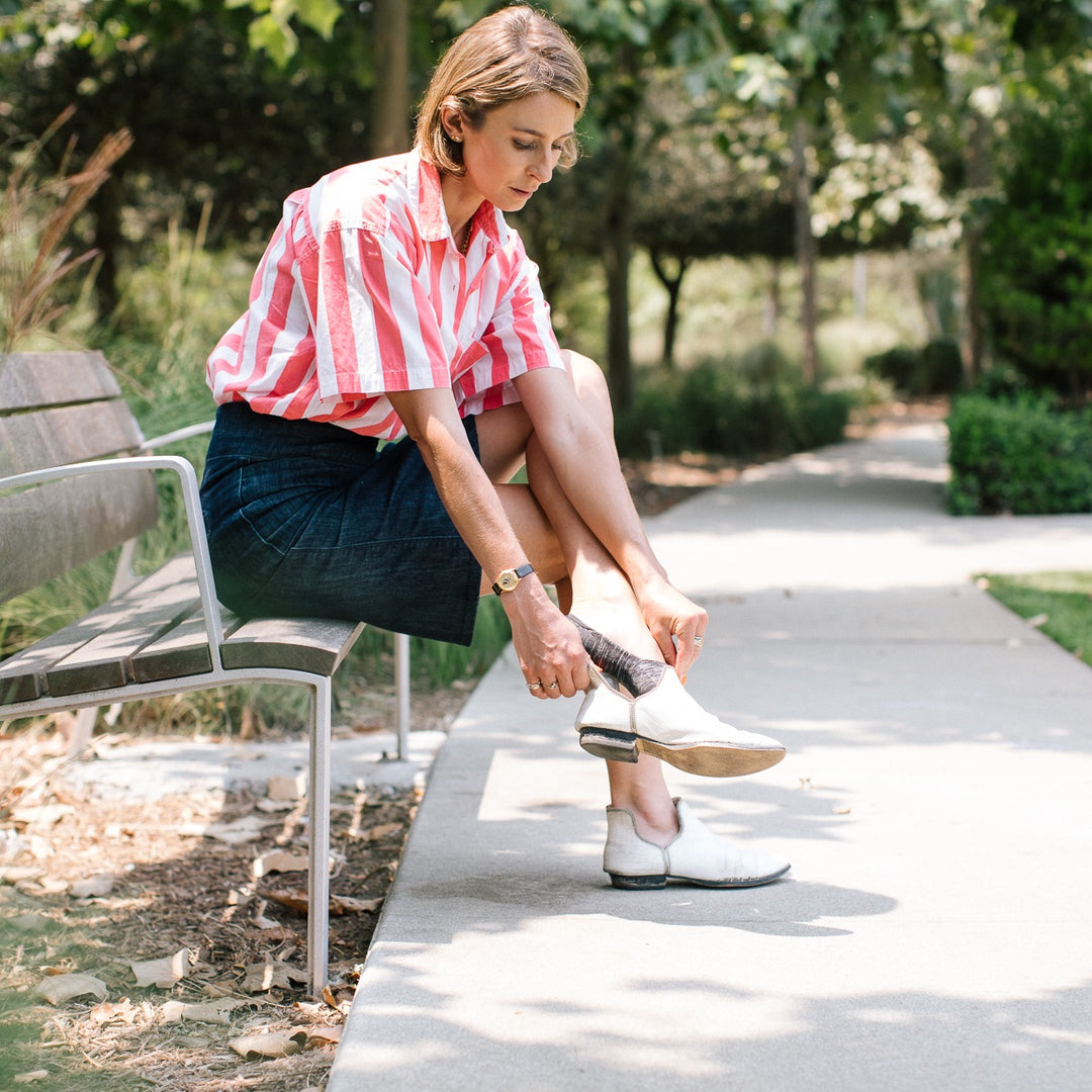 Woman seated on park bench adjusting shoes and wearing darn tough socks, a great Mother's Day gift