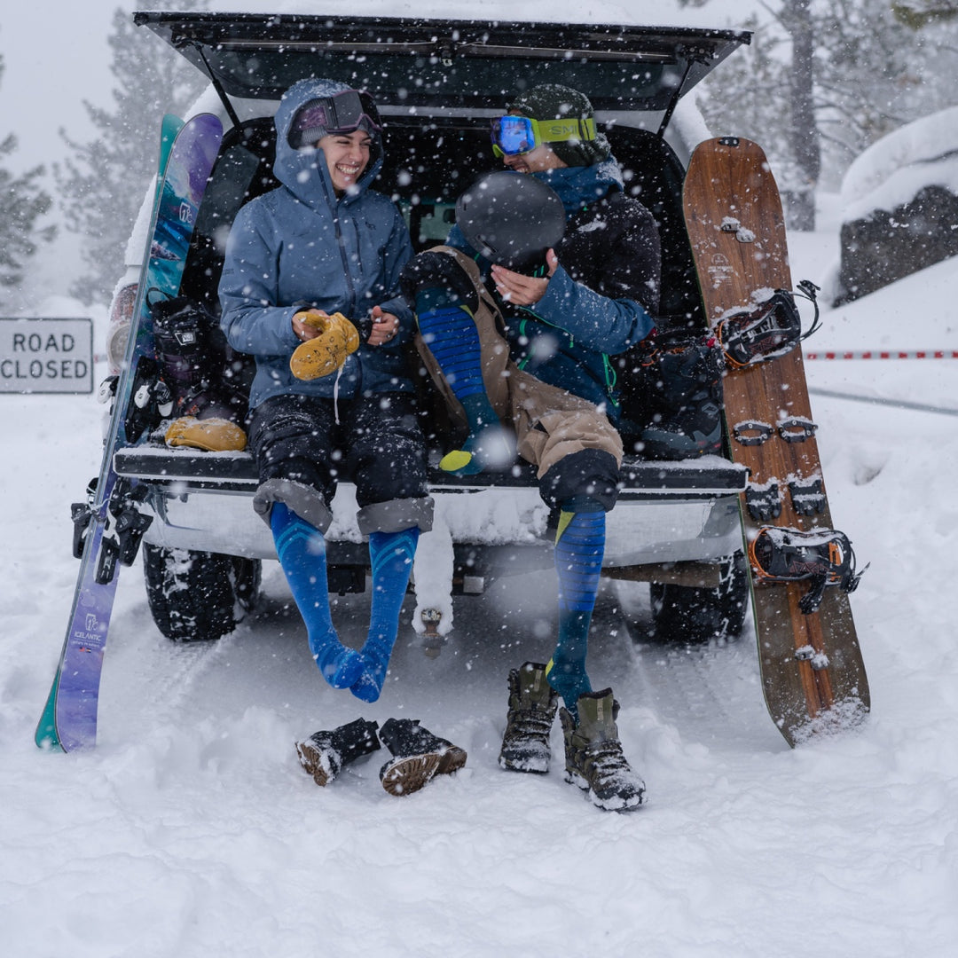 A skier and a snowboarder wearing merino wool socks for winter as it snows