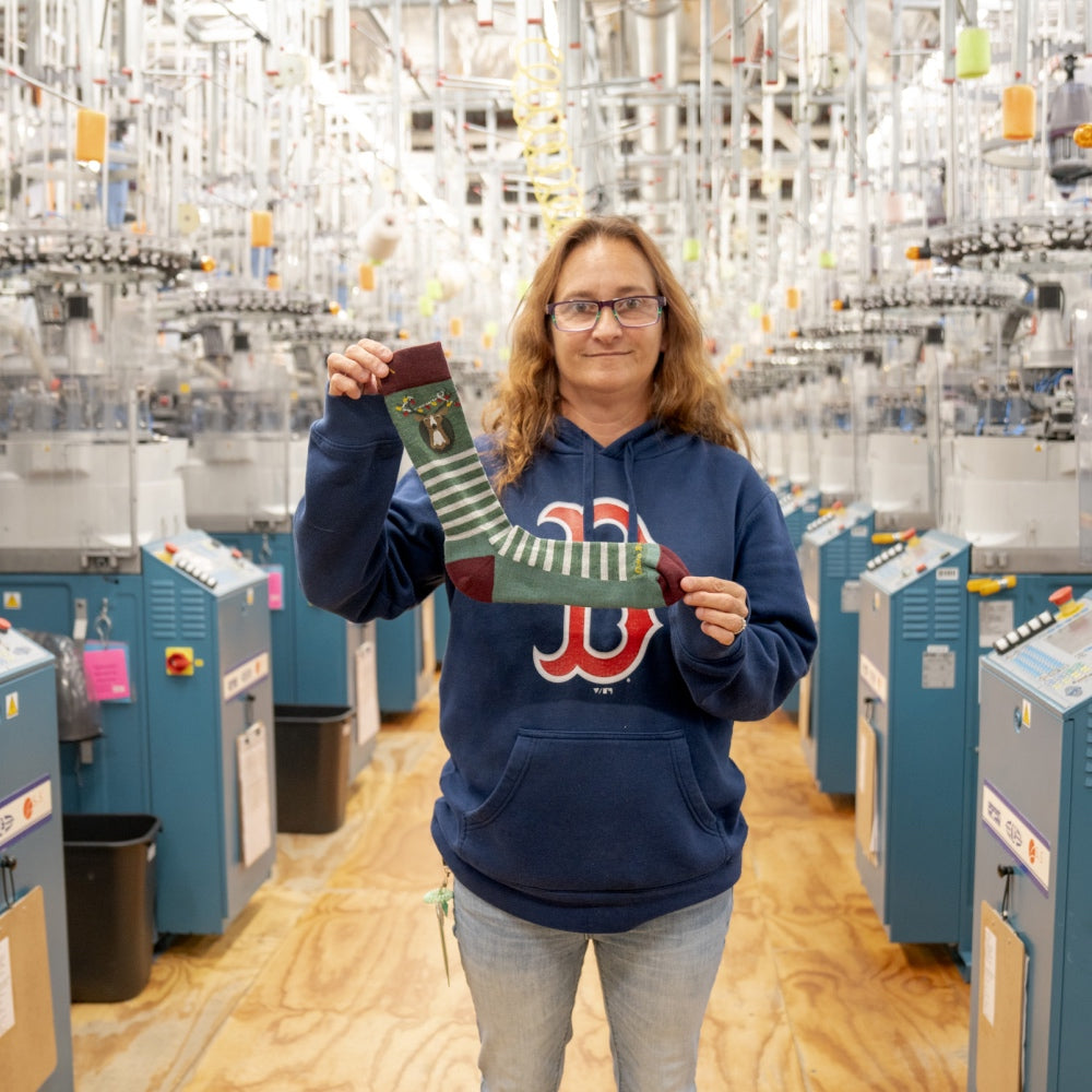 A Darn Tough employee at the Mill holding up a Christmas sock, her favorite