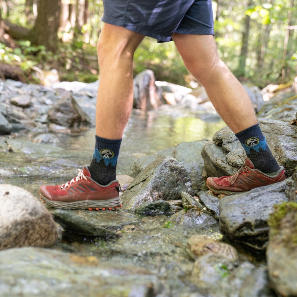 Hiker crossing a stream wearing long lasting socks from Darn Tough Vermont