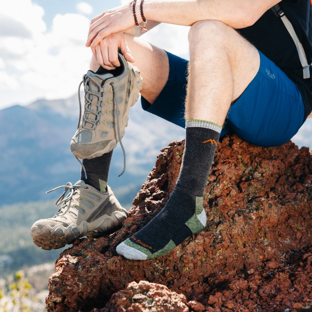 Hiker seated on rock with one boot off, showing his hiking socks