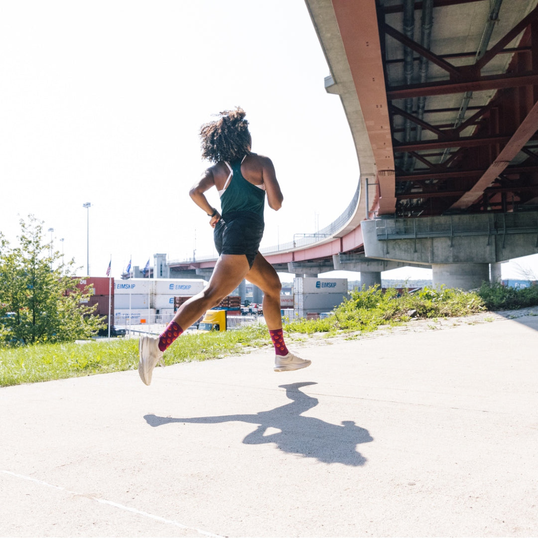 Woman starting her run, headed out in pink socks as she passes under a bridge