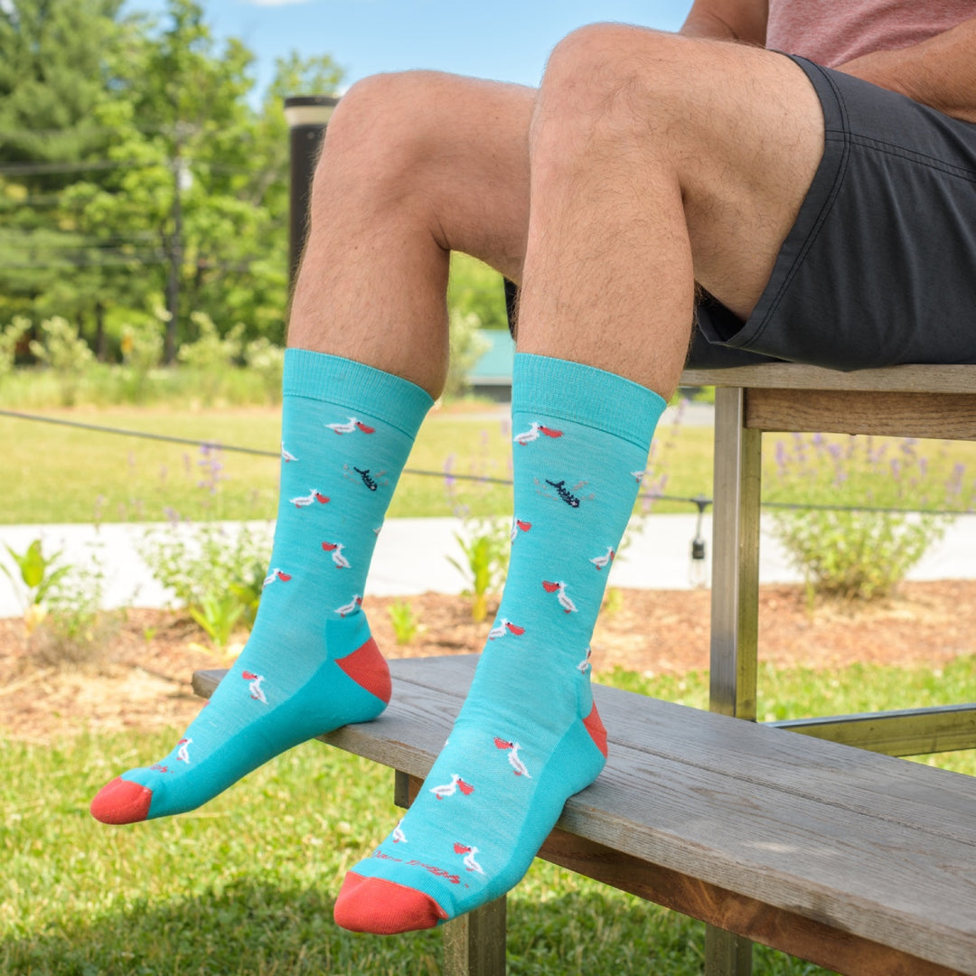 Feet on a sunny day wearing bright socks, in vibrant blue and salmon with a pelican pattern