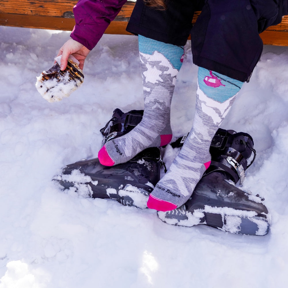 A skier's hand reaching down to pick up a waffle dropped on the snowy ground... Darn It.