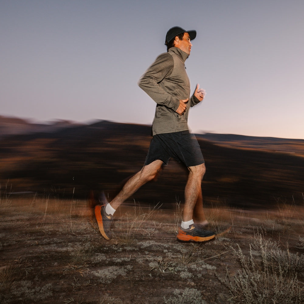 A man running across a landscape at sunrise wearing the best men's running socks