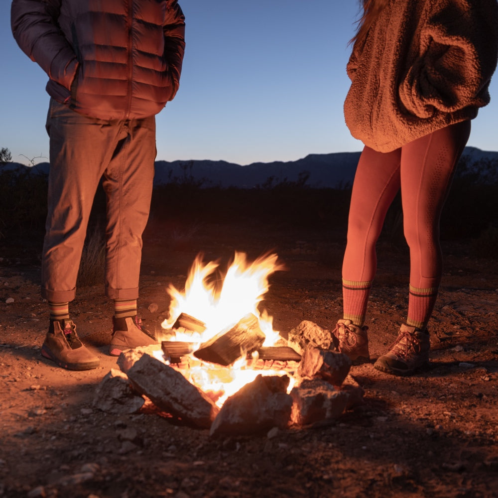 A couple standing around a campfire wearing coordinated hiking socks