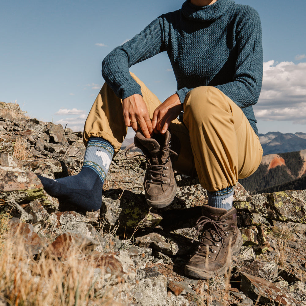 A hiker seated, boot off, showing the Vanna Grizzle goat socks