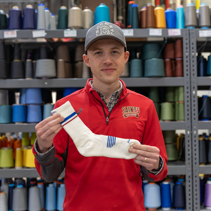 A Darn Tough employee holding up his favorite running socks, a white micro crew