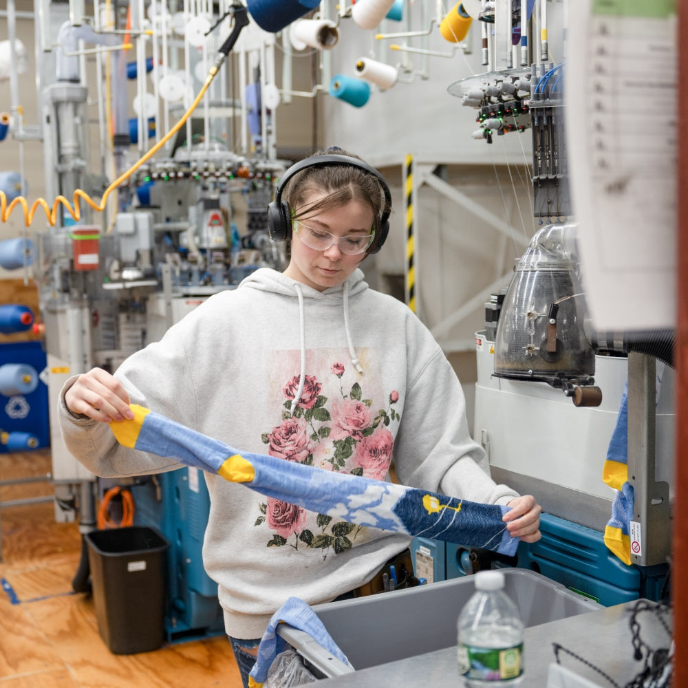 A woman at the Darn Tough Mill examining a sock that's just been knit
