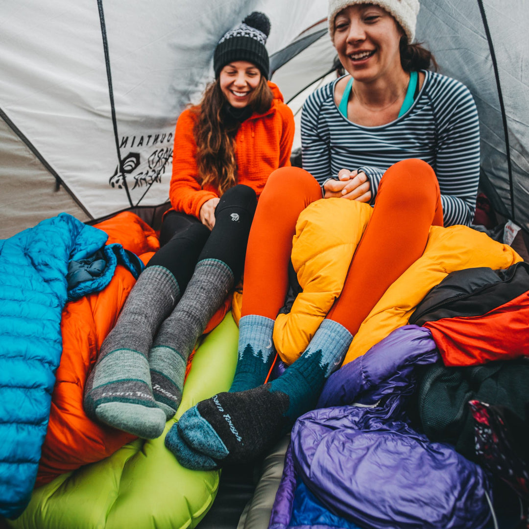 two friends sitting in a tent wearing darn tough socks