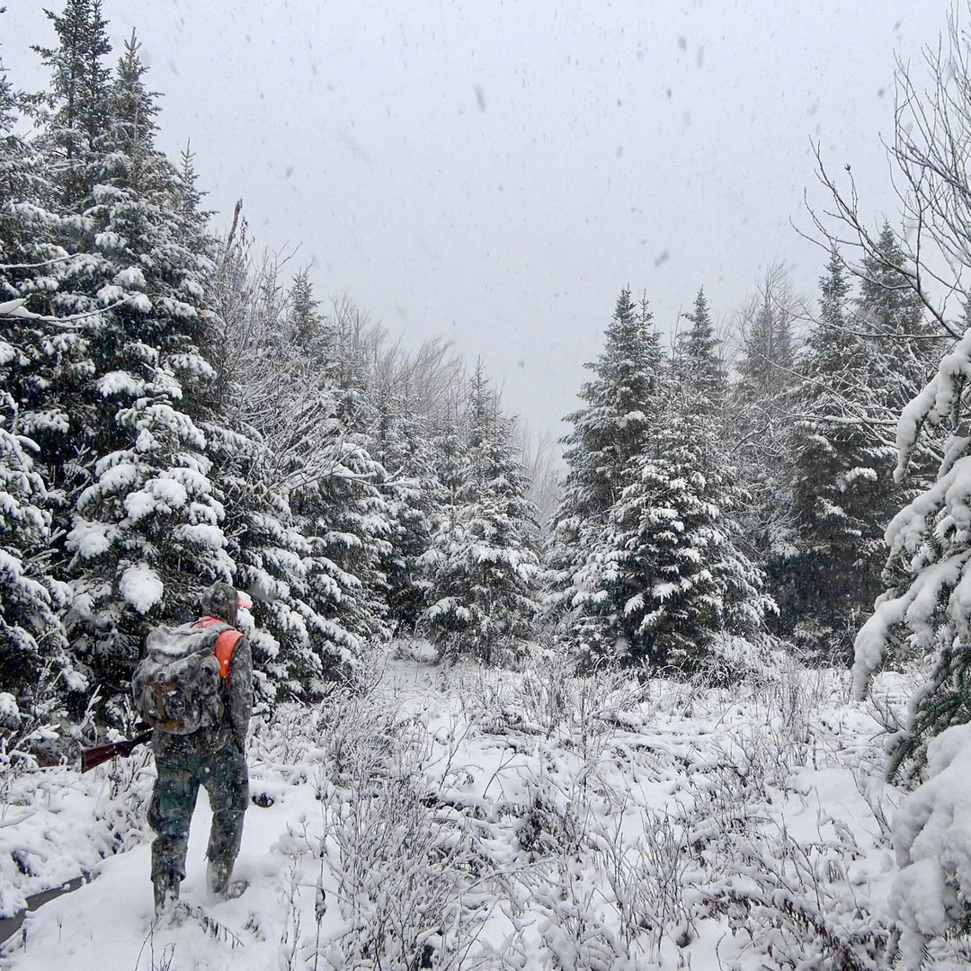 Northwoods Whitetail hunter walking through deep snow wearing merino wool socks and clothes