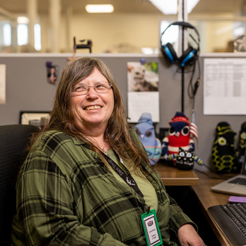 Laura seated at her desk in the Mill, smiling