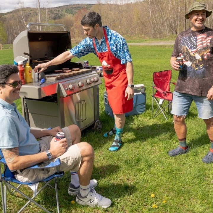 Three dads standing around a grill drinking beers