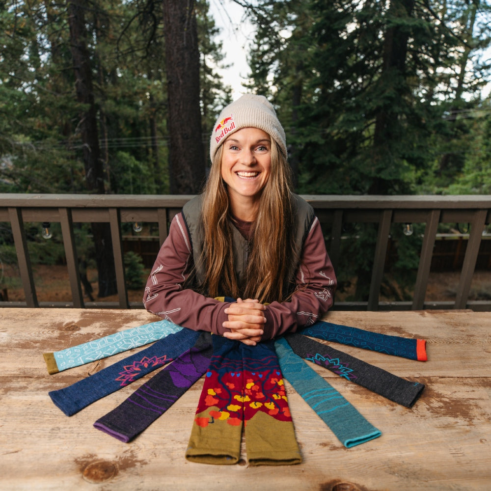 Michelle Parker sitting on her back porch surrounded by the 7 socks she helped design