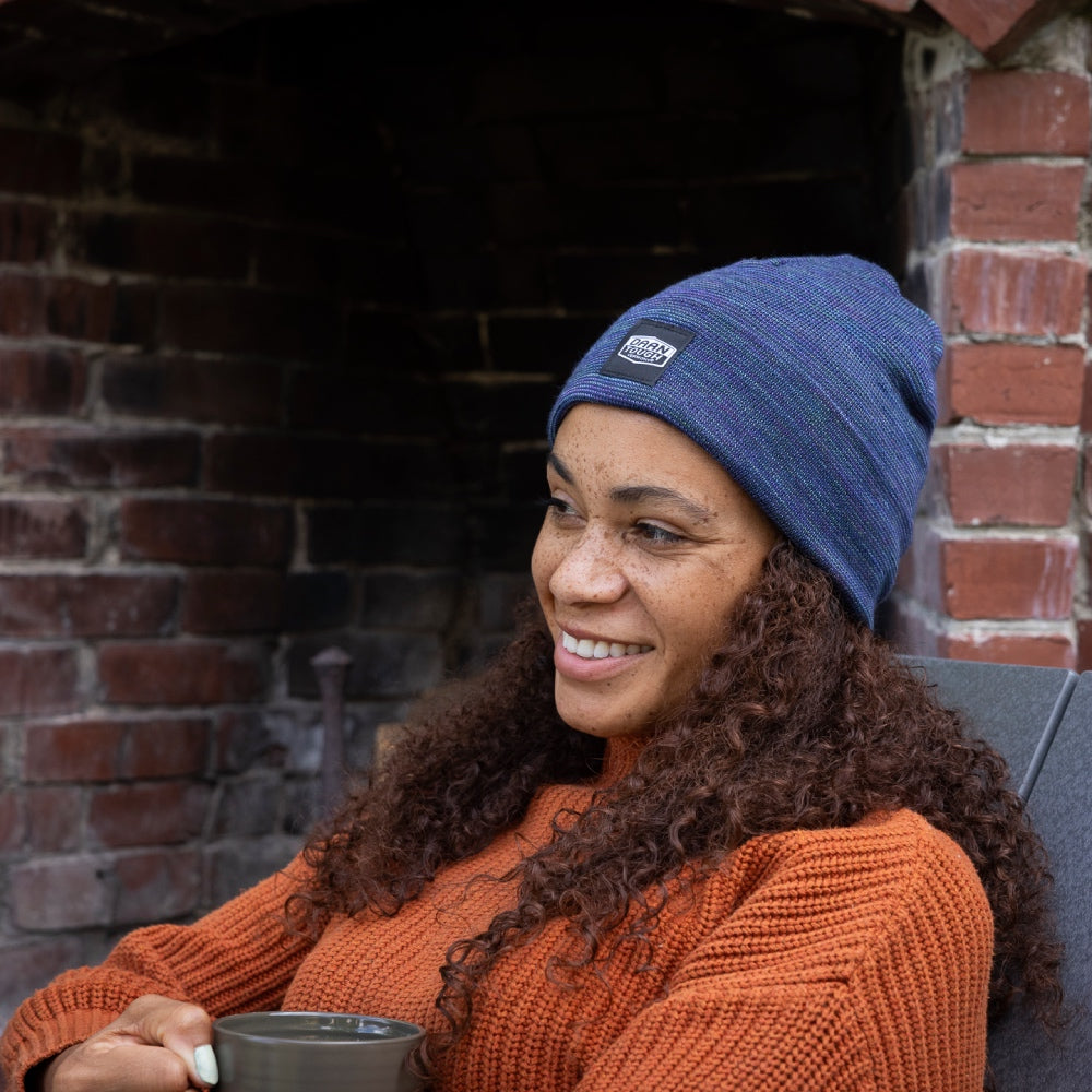 A woman wearing a blue heather Merino Wool beanie with the Darn Tough logo
