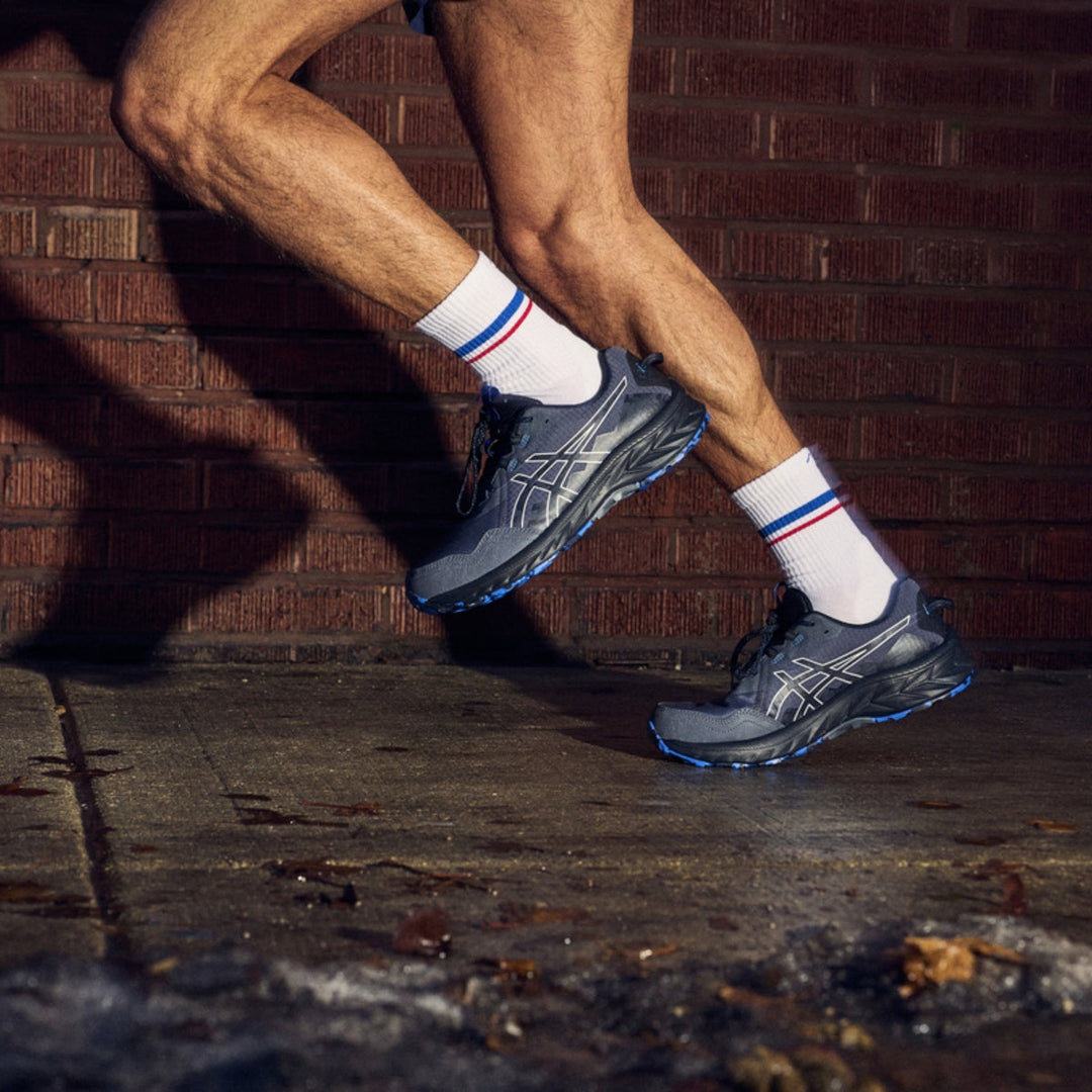 Person running on wet pavement wearing white running socks and sneakers.