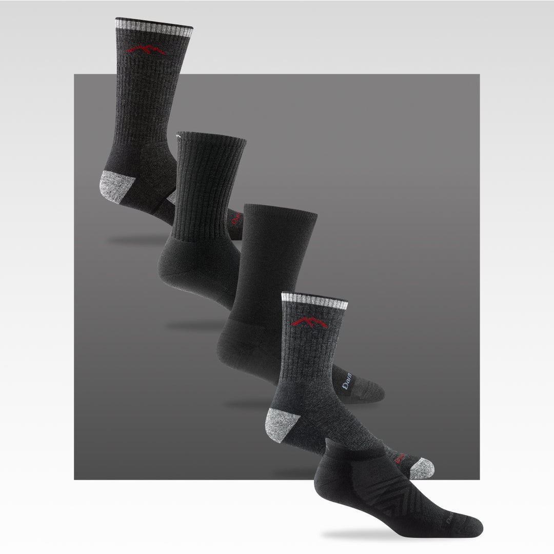 five examples of black socks from darn tough, on a grey background (of course)