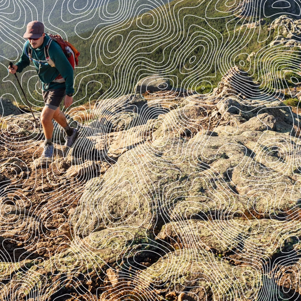 A hiker headed up a mountain Vermont with topographical lines drawn over the image