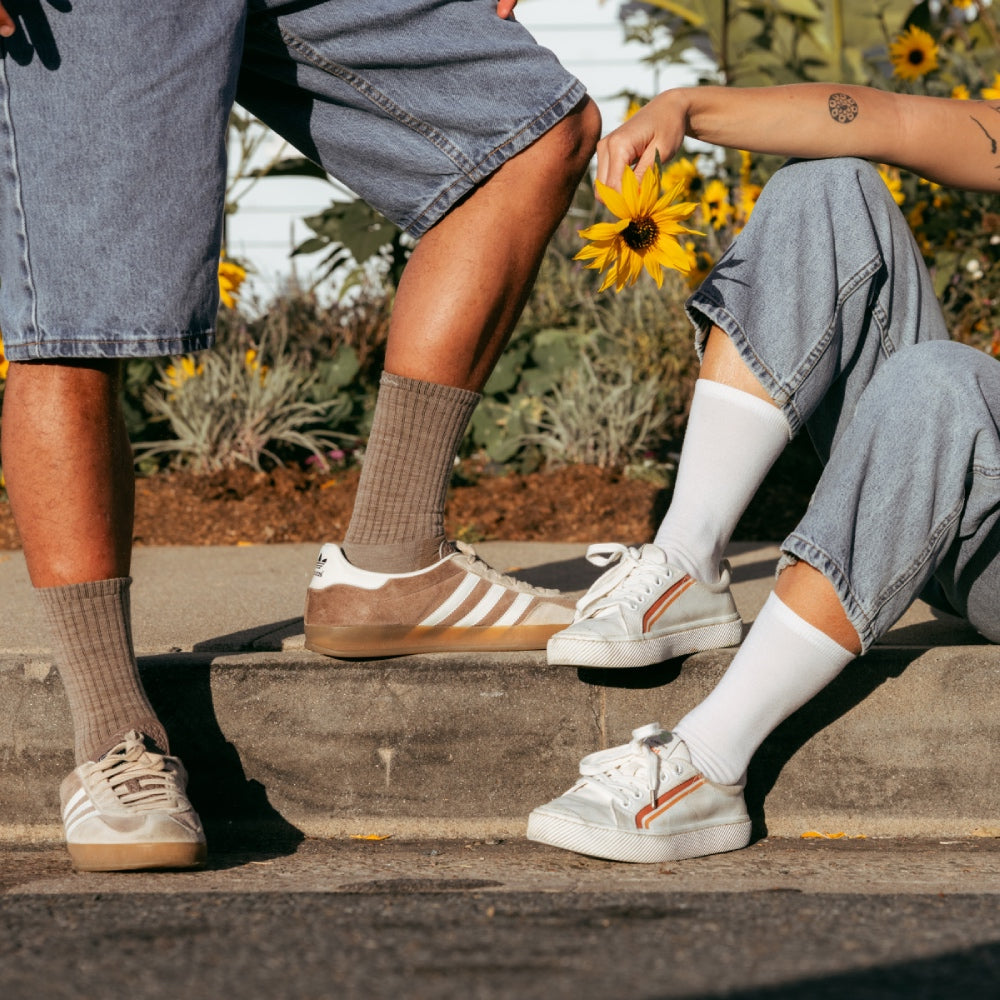A couple seated by flowers wearing Darn Tough coordinated socks in brown and white