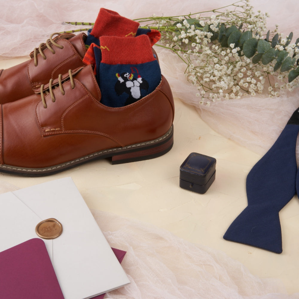 Funky men's dress socks laid out with dress shoes and a bow tie