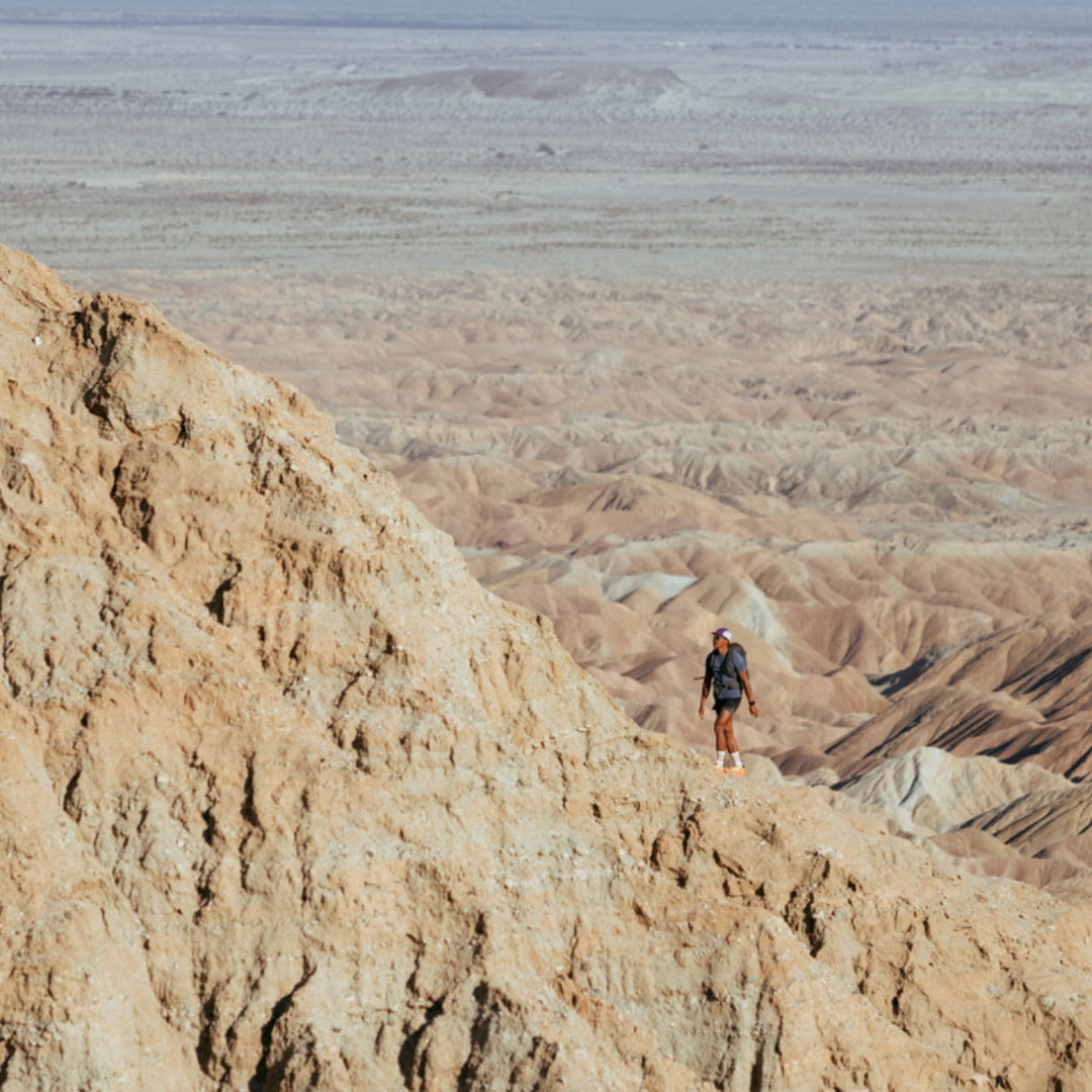 Hiker walking up mountain in the desert with a vast view.