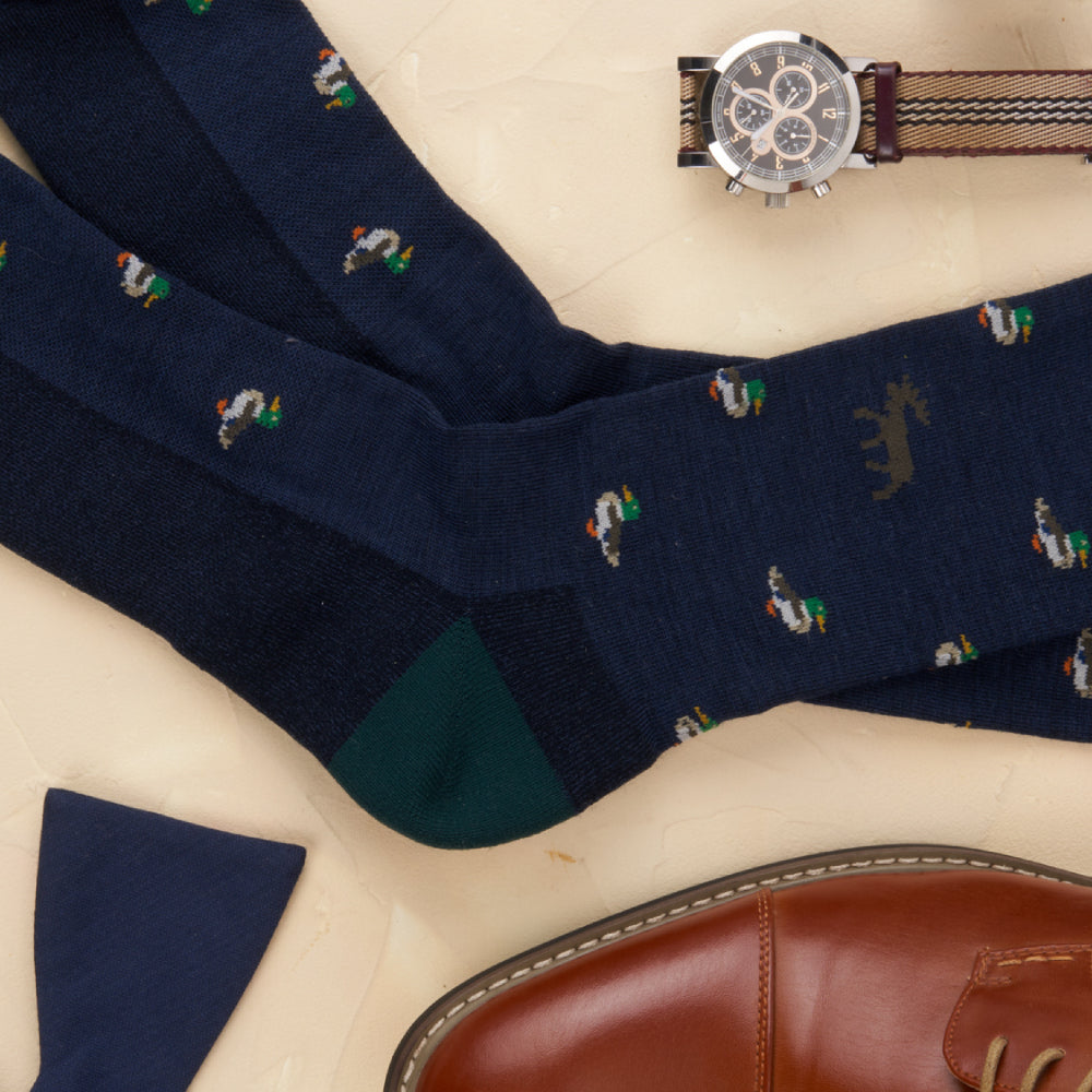 Men's dress socks laid out with dress shoes, a bow tie, and a watch