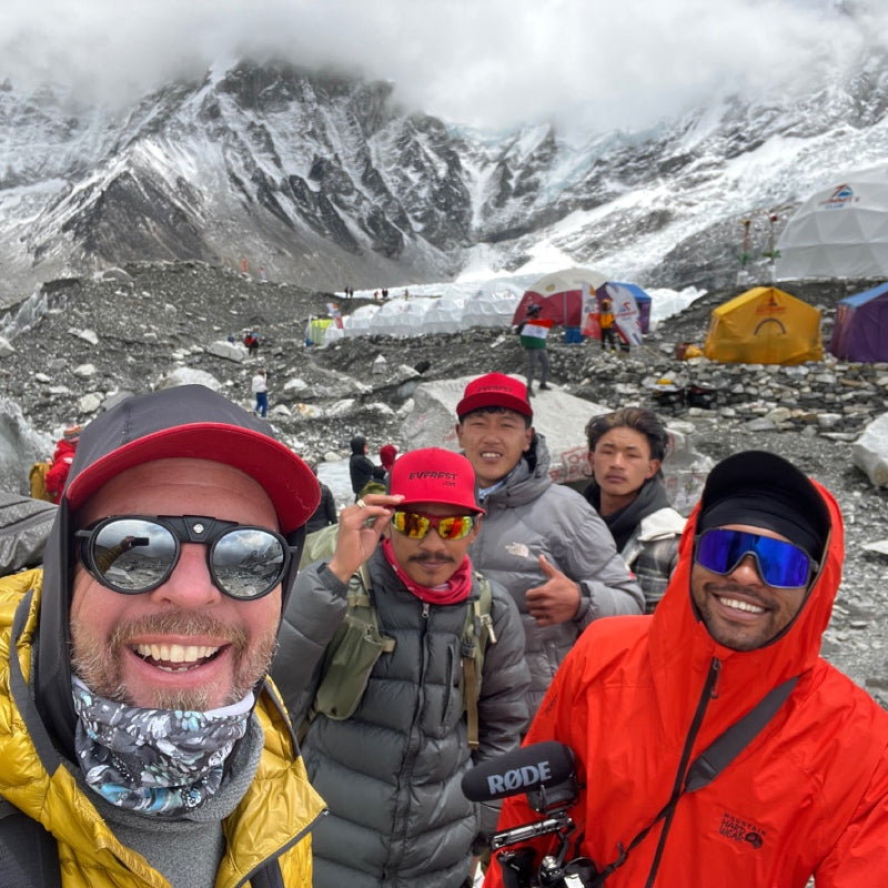 Ben and his crew smiling with Everest Base Camp behind them