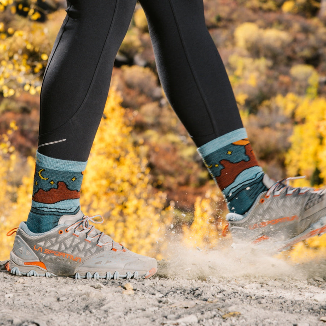 Hiker kicking up dirt walking on a dusty, rocky trail while wearing micro crew hiking socks.