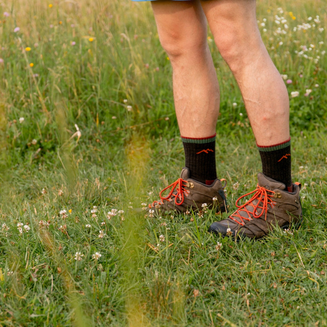 Hiker standing on grassy trail wearing hiking boots and micro crew hiking socks.