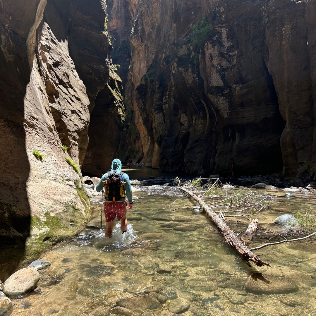 Hiker walking through a river of water in a cavern.