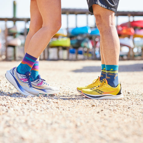 A couple facing each other, only their feet visible, wearing coordinated darn tough socks