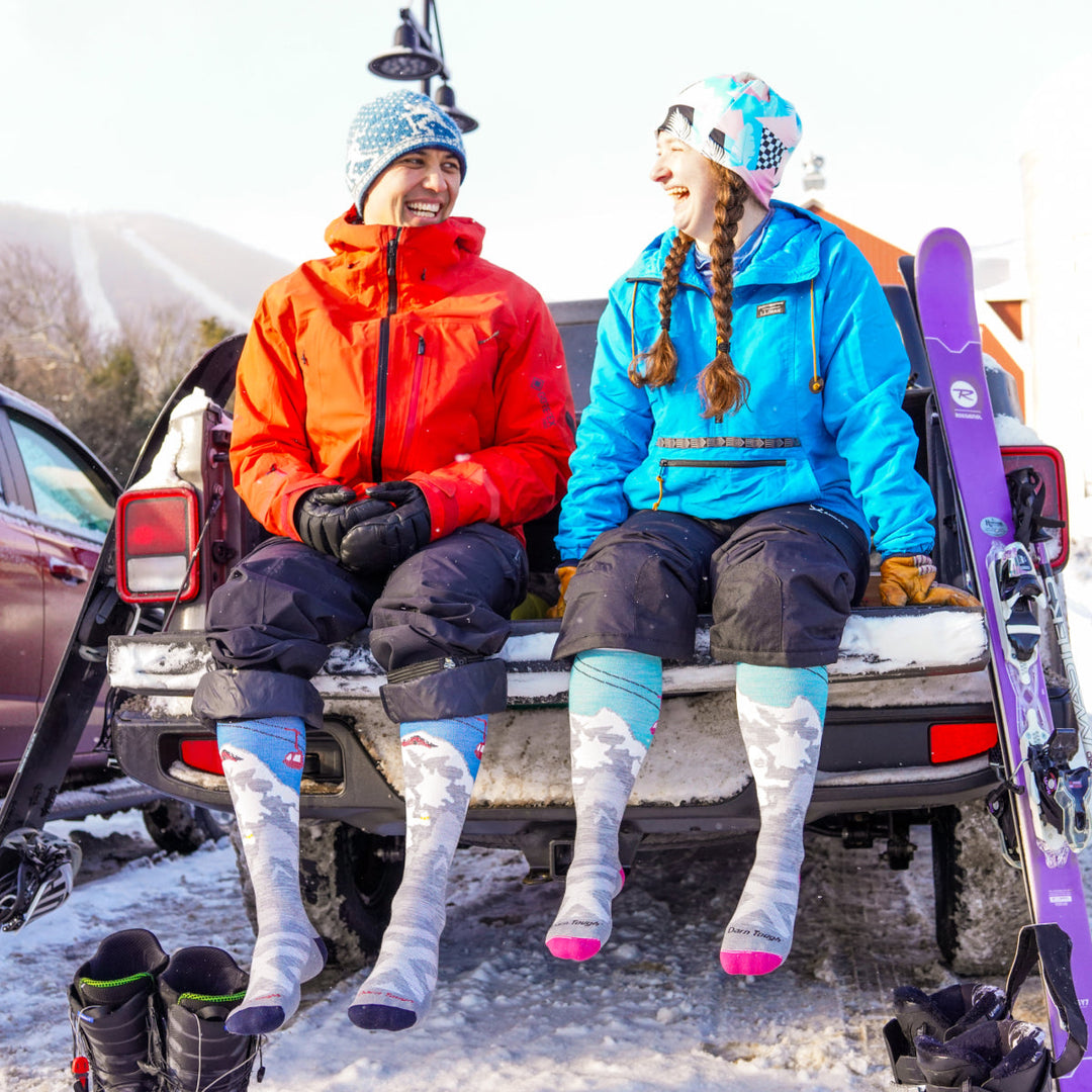 A couple sitting on a truck bed wearing coordinated Merino Wool socks on a winter day
