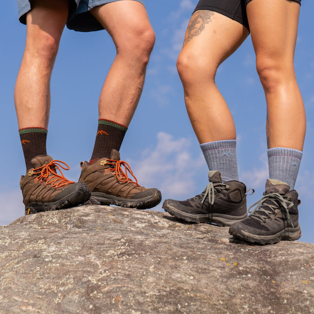 A man and a woman on a rock wearing Micro Crew height socks from Darn Tough
