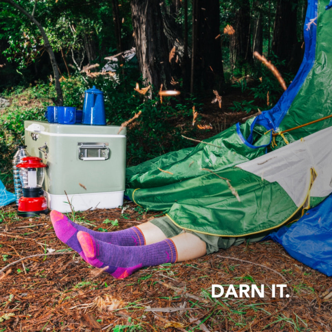Legs wearing pink hiking socks sticking out from under a collapsed tent with Darn It. text overlay.