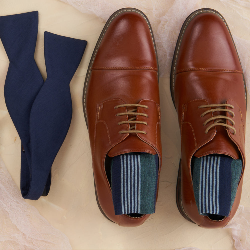 Men's dress shoes laid out with coordinated socks and accessories for an event