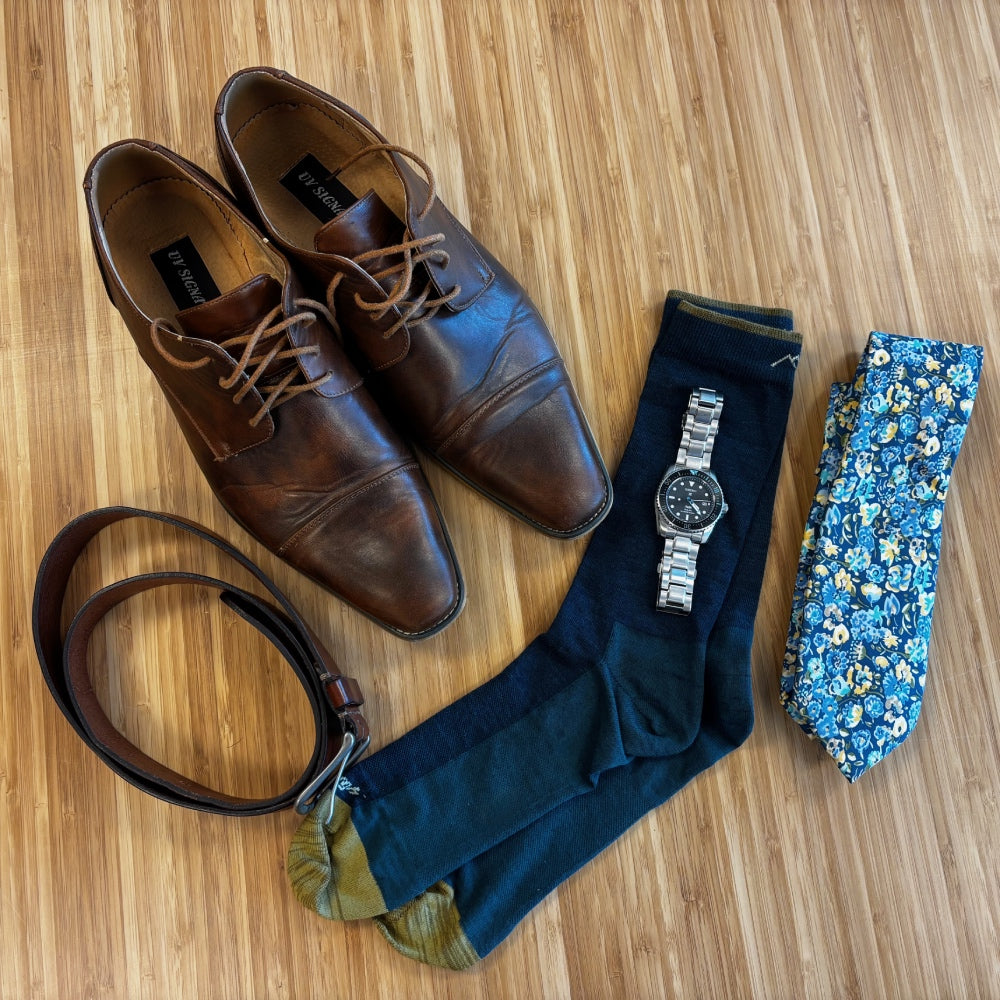 Dress socks laid out with shoes, a watch, tie, and belt