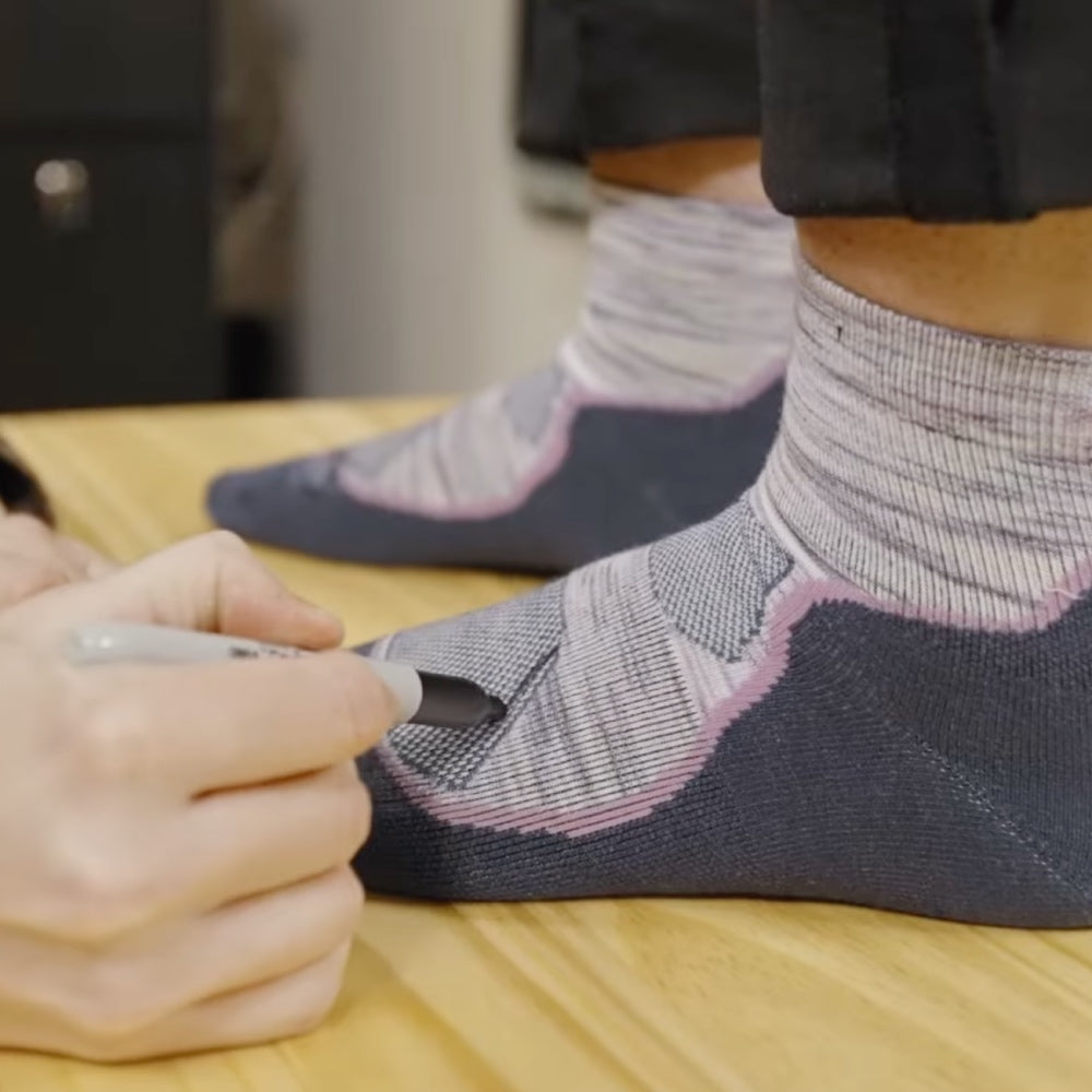 Person wearing space dye socks in purple while another person marks up the socks