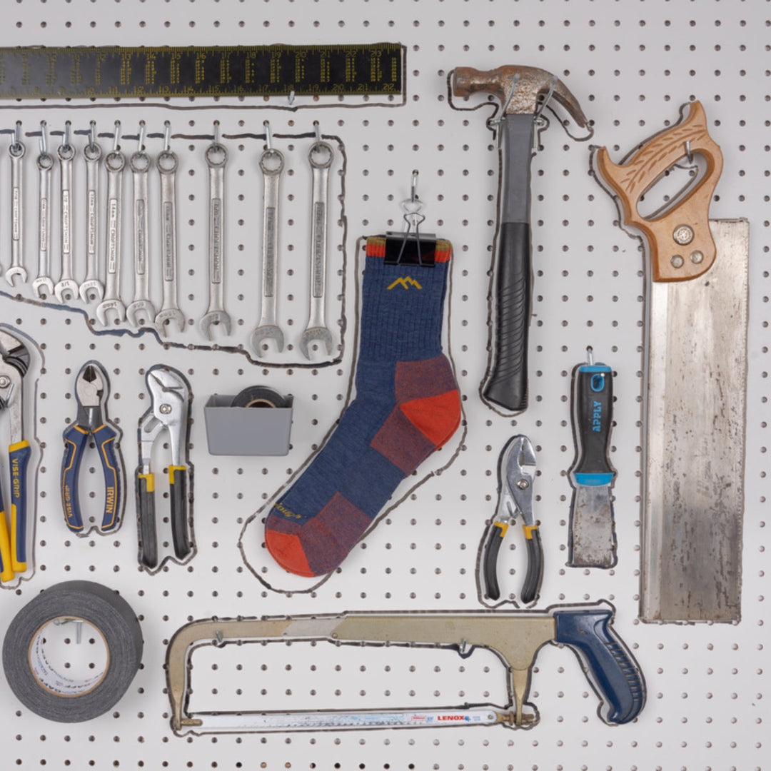 Sock pinned up and hanging on a wall of tools.
