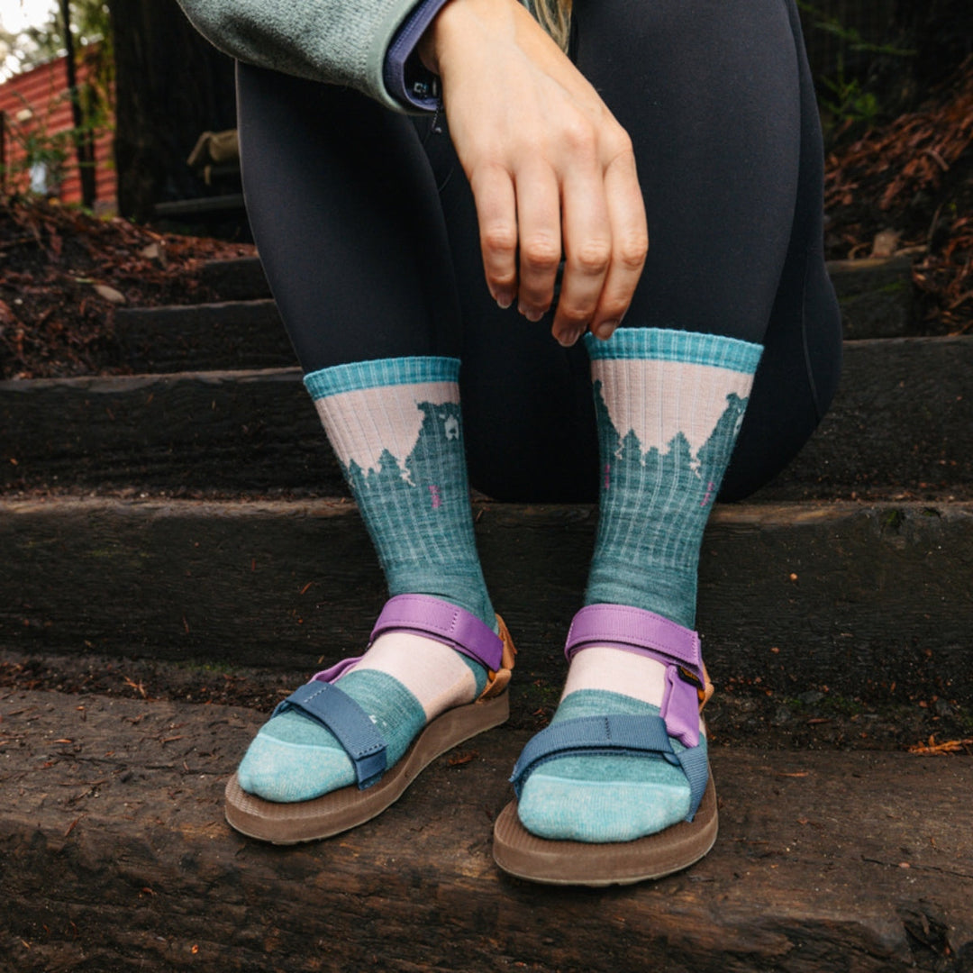 Hiker sitting on steps wearing hiking socks with sandals.
