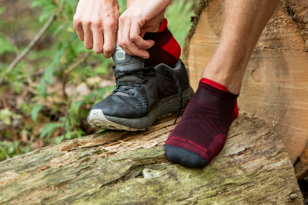 A trail runner putting on shoes over his red darn tough running socks, the perfect Valentine's Day gifts for him