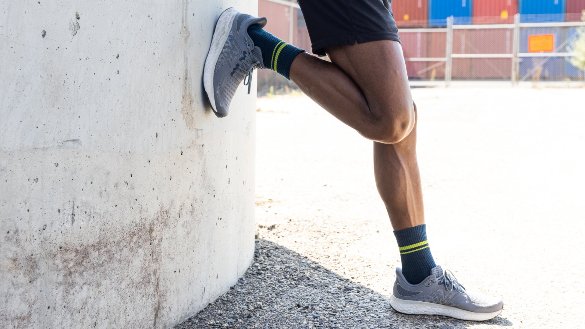 Model standing with one foot back to the wall wearing the Men's Element lightweight athletic crew sock