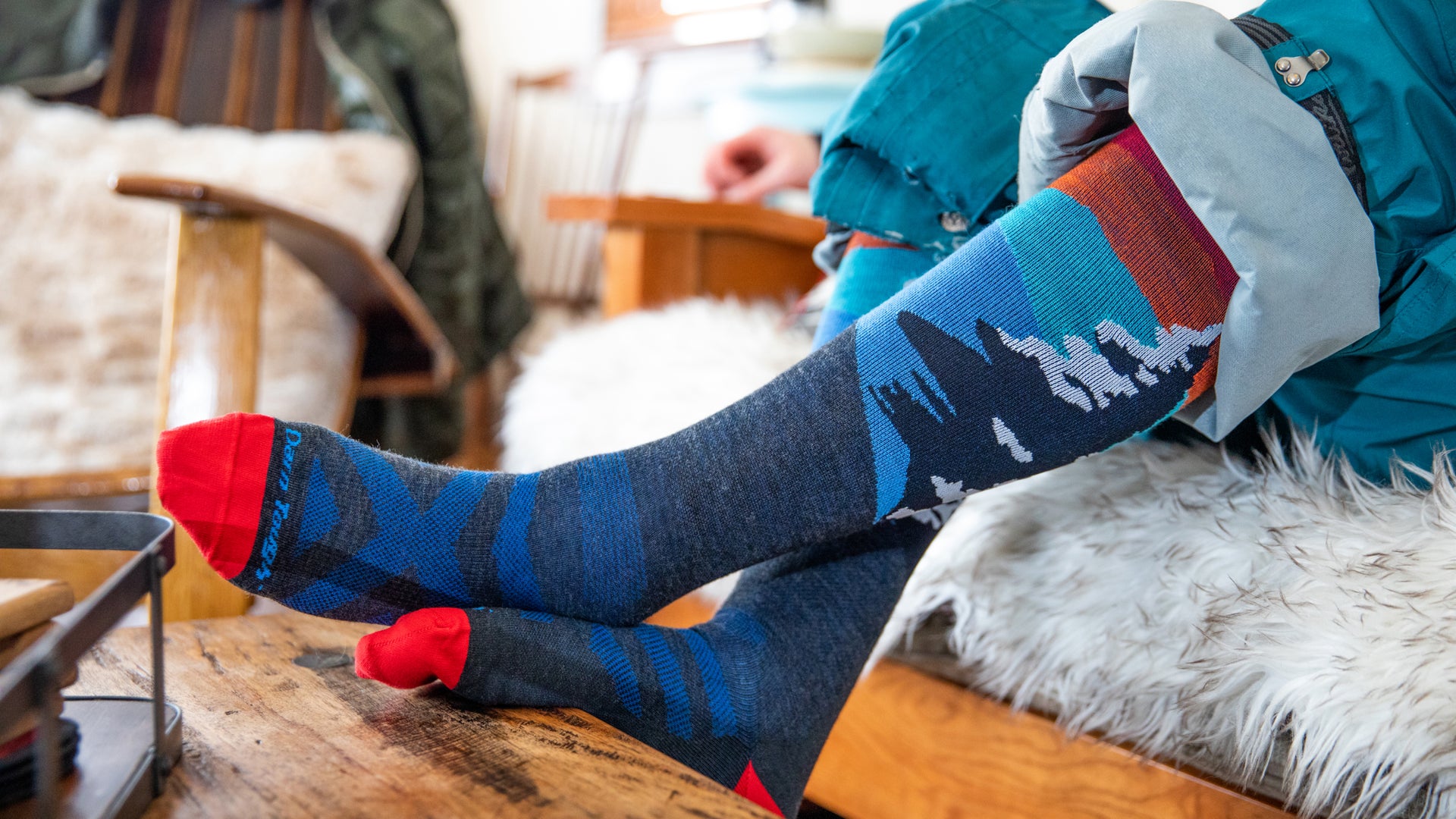 Skier and snowboarder pulling on boots over their merino wool ski socks and snowboard socks