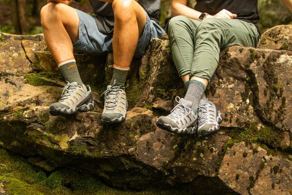 A couple of hikers sitting on a rock wearing hiking boots and darn tough hiking socks, the perfect matching couples gifts for valentines day