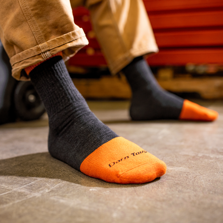 Worker's feet wearing micro crew steely work boots in graphic black and orange