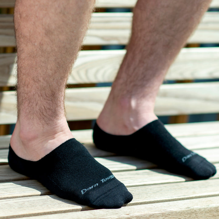Man's feet wearing no show hidden black socks for everyday and dress shoes